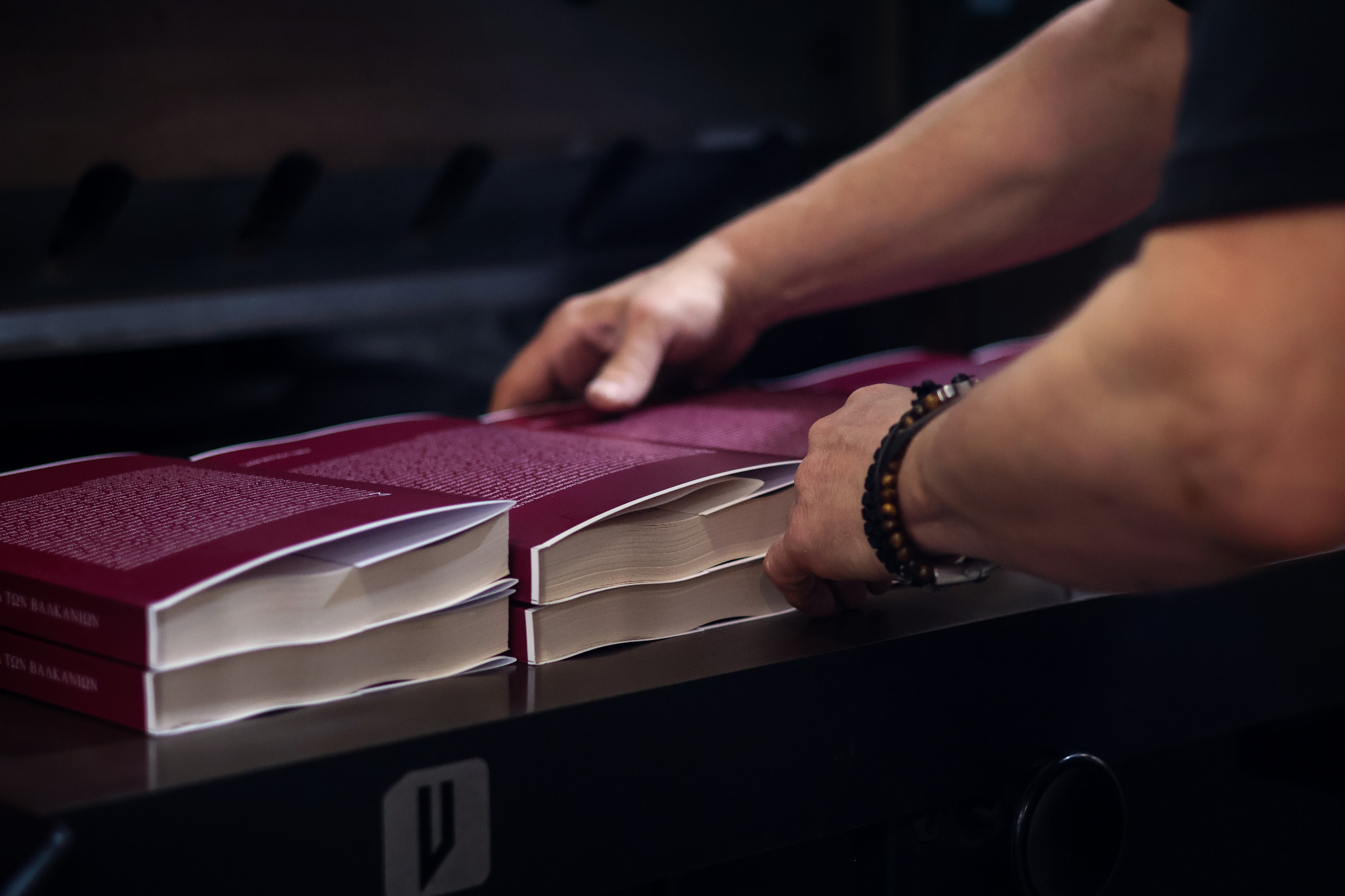 Mains manipulant des livres imprimés sur une table de reliure